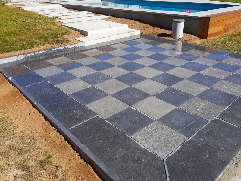 Realization of a chessboard terrace with slabs of Belgian Blue Stone bushhammered and softened light blue
